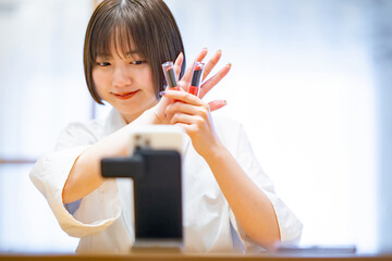 スマートフォンを使ってコスメグッズを紹介する女性 
