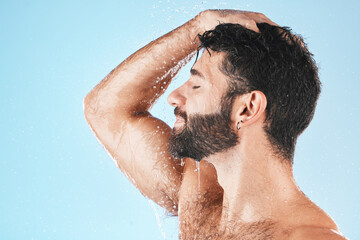 Head, hair and hygiene with a model man using shampoo for cleaning in studio on a blue background. Water, wet and wellness with a handsome male washing for haircare, hydration or keratin treatment