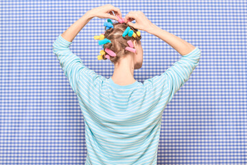 Young woman rolling bright colorful hair curlers into her hair