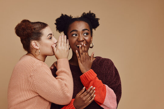 Friends, gossip and women share secret on studio background and product placement mockup. Secrets, rumor and surprise whisper in ear, black woman with happy woman discuss discount sale announcement