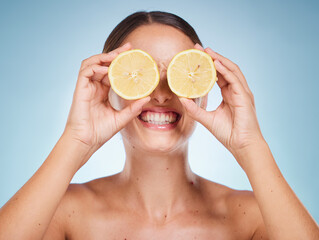 Beauty, lemon and skincare with a model woman in studio on a blue background for natural treatment. Wellness, luxury and fruit with an attractive young female posing to promote health or skin care