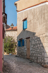 The street rising on the hill and blue wooden shutters