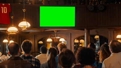 Group of Multicultural Friends Watching a Live Sports Match on TV with Green Screen Display in a Bar. Happy Fans Cheering and Shouting, Celebrating When Team Scores a Goal and Wins the Tournament.