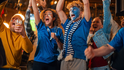 Close Up on a Group of Supportive Soccer Fans with Painted Blue and White Faces Standing in a Bar, Cheering for Their Team. Raising Hands and Shouting. Friends Celebrate Victory After the Goal.