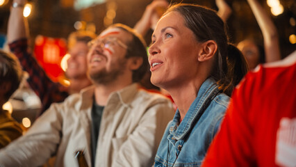 Young Soccer Fans Couple Watching a Live Football Match in a Sports Bar. Crowd with Colored Faces Cheering for Their Team. Player Scores a Goal and Crowd Celebrate Winning the Championship.