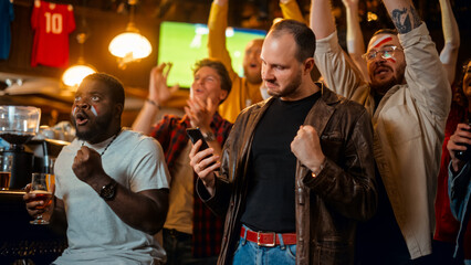 Portrait of a Emotional Young Man Holding a Smartphone, Happy About the Sports Bet on a Soccer Match. Looking Like an English Pub Regular, Wearing a Stylish Leather Jacket.