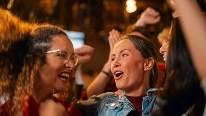 Three Female Friends Watching a Live Soccer Match on TV in a Sports Bar. Happy Girls Cheering and Shouting. Young Fans Celebrating When Team Scores a Goal and Wins the Football World Cup.