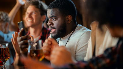 Portrait of an Excited Young Black Man Holding a Smartphone, Stressed About a Sports Bet on His Favorite Soccer Team. Lively Successful Emotions When Football Team Scores a Winning Goal.
