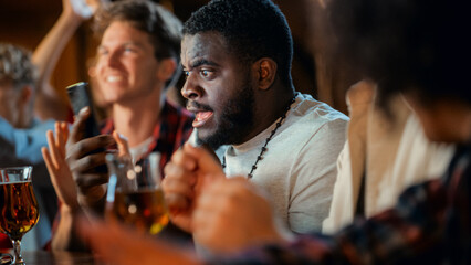 Portrait of an Excited Young Black Man Holding a Smartphone, Stressed About a Sports Bet on His...