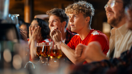 Group of Young Friends Watching a Live Soccer Match on TV in a Sports Bar. Excited Fans Cheering and Shouting. Young People Celebrating When Team Scores a Goal and Wins the Football Championship.