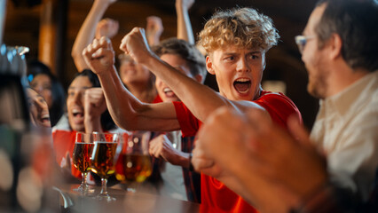 Group of Young Friends Watching a Live Soccer Match on TV in a Sports Bar. Excited Fans Cheering and Shouting. Young People Celebrating When Team Scores a Goal and Wins the Football Championship.