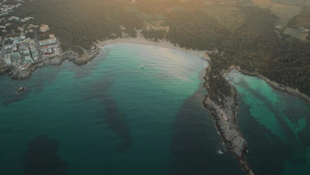 Picturesque drone point of view Cala Agulla is a beautiful beach in Majorca. Aerial shot green Mediterranean Sea at sunny day. Spain. Balearic Islands