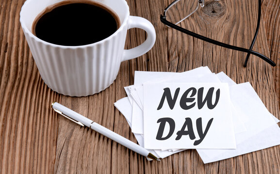 NEW DAY text on sticky with coffee and pen on wooden background