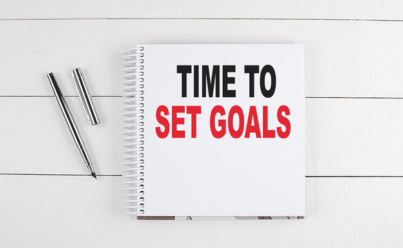 TIME TO SET GOALS text written on notebook on the wooden background