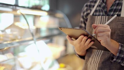 female restaurant or coffee shop staff inspecting a bakery stock inventory in refrigerator at counter bar. - Powered by Adobe