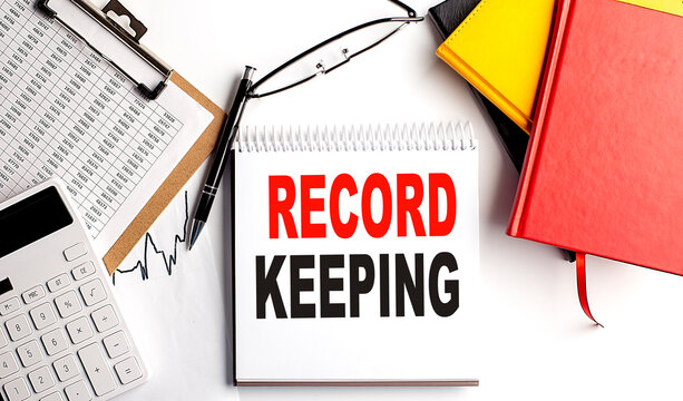 RECORD KEEPING text on notebook with clipboard and calculator on white background