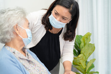 Fototapeta premium Caregiver help Asian senior or elderly old lady woman sitting on wheelchair and wearing a face mask for protect safety infection Covid19 Coronavirus.