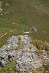 Green mid-mountain landscape under the sun without trees. Hiking trails descend to the valley through mountain meadows.