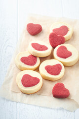 Valentines day cookies. Shortbread cookies inside a sweet red heart on parchment paper on white background. Mothers day. Womans day. Sweet holidays baking. Top view.