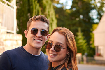 A smiling hispanic couple with sunglasses in the street