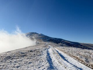 Winter road in the mountains. Above the clouds. Carpathians, Polonynian Beskids, Ukraine.
