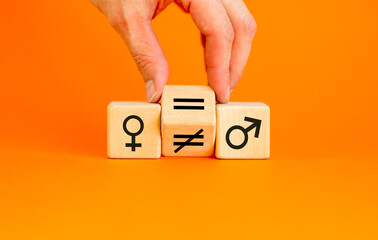 Symbol for gender equality. Turned a cube and changed a unequal sign to a equal sign between symbols of men and women. Beautiful orange table orange background, copy space. Gender equality concept.