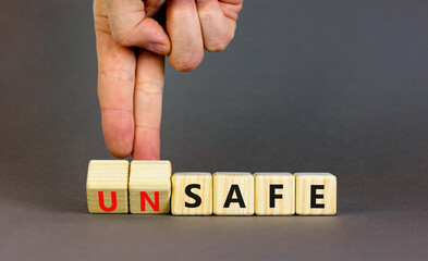 Safe or unsafe symbol. Concept word Safe Unsafe on wooden cubes. Businessman hand. Beautiful grey table grey background. Business safe or unsafe concept. Copy space.