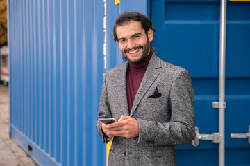Man in blazer using smartphone and looking at camera