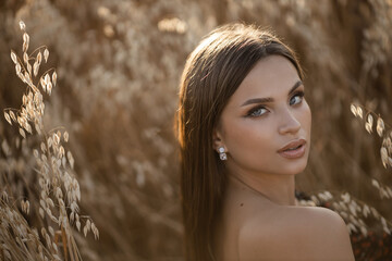 beautiful young woman with makeup in a field with wheat	