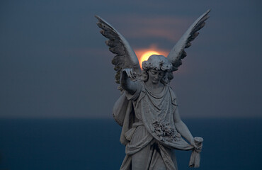 tombstone statue with red moon rising between wings