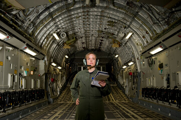 A U.S. Air Force loadmaster runs down her checklist in the cargo area during preflight.