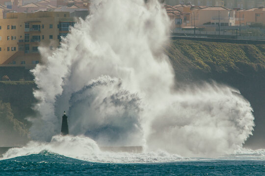 A massive wave breaks against a lighthouse