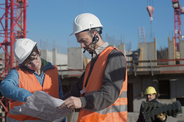 Two engineers looking at a blueprint at construction site, Freiburg Im Breisgau, Baden-Württemberg, Germany