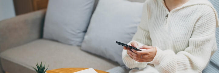 Happy asian woman using mobile phone and receiving good news.on sofa at living room