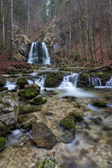 Wasserfall mit Flussbett mit Felsen und Moos im Herbst.