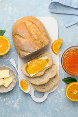 Sliced bread with butter and orange jam on a white board on a blue background. Tasty breakfast. Top view