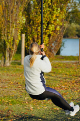 Young woman on swing in park with lake in background. Outdoor activity. Hobbies and entertainment....