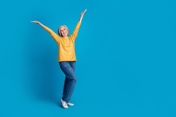 Fototapeta na wymiar Full length photo of satisfied glad aged lady raise arms empty space novelty isolated on blue color background