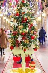 Christmas tree with balerina legs on bottom and Christmas decor. group of people walking through a shopping mall next to a christmas tree. © GMars