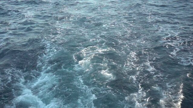 Wake of vessel. Wide wake trail from boat. Back view. Ocean water. Deep blue. Trace from large ship.