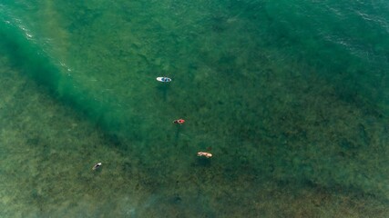 Aerial view of turquoise water of Pacific Ocean, Sri Lanka. A group of surfers are waiting for the waves from above.