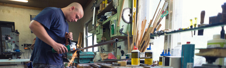 Young carpenter cutting metal bars for furniture in his workshop	