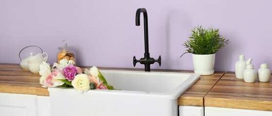 Clean sink with beautiful bouquet of fresh flowers in interior of modern kitchen