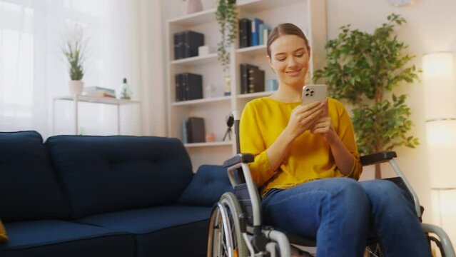 Happy young woman in wheelchair using mobile app, playing a game on smartphone
