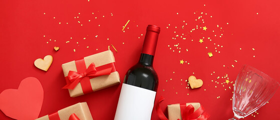 Composition with bottle of wine, glass, hearts and gifts on red background. Valentine's Day celebration