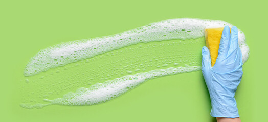 Hand with sponge cleaning green surface