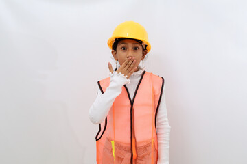 Shocked Asian little girl in the construction helmet as an engineer standing while covering her mouth. Isolated on white