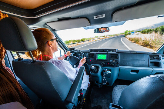 Woman Is Driving Motorhome Or Campervan On The Road Outdoors In Nature.