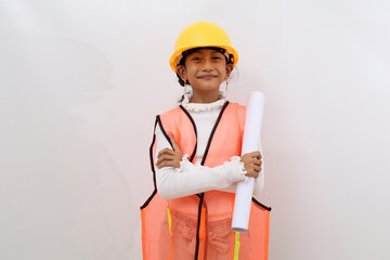 Happy Asian little girl in the construction helmet as an engineer standing while holding a blueprint paper. Isolated on white