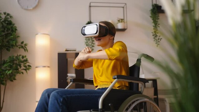 Positive woman in wheelchair playing virtual reality game, martial arts, boxing